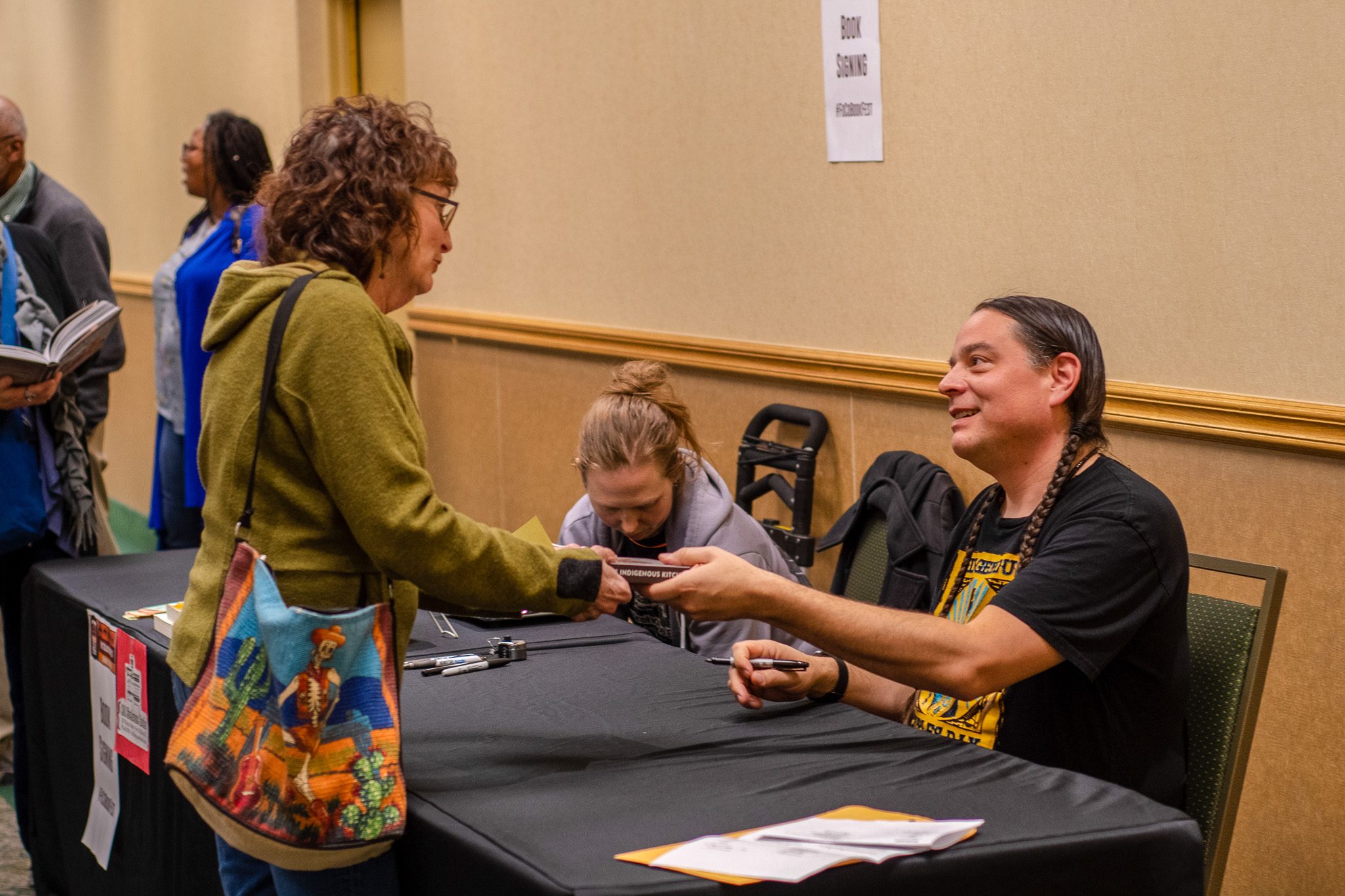 woman handing book to an author to have it signed