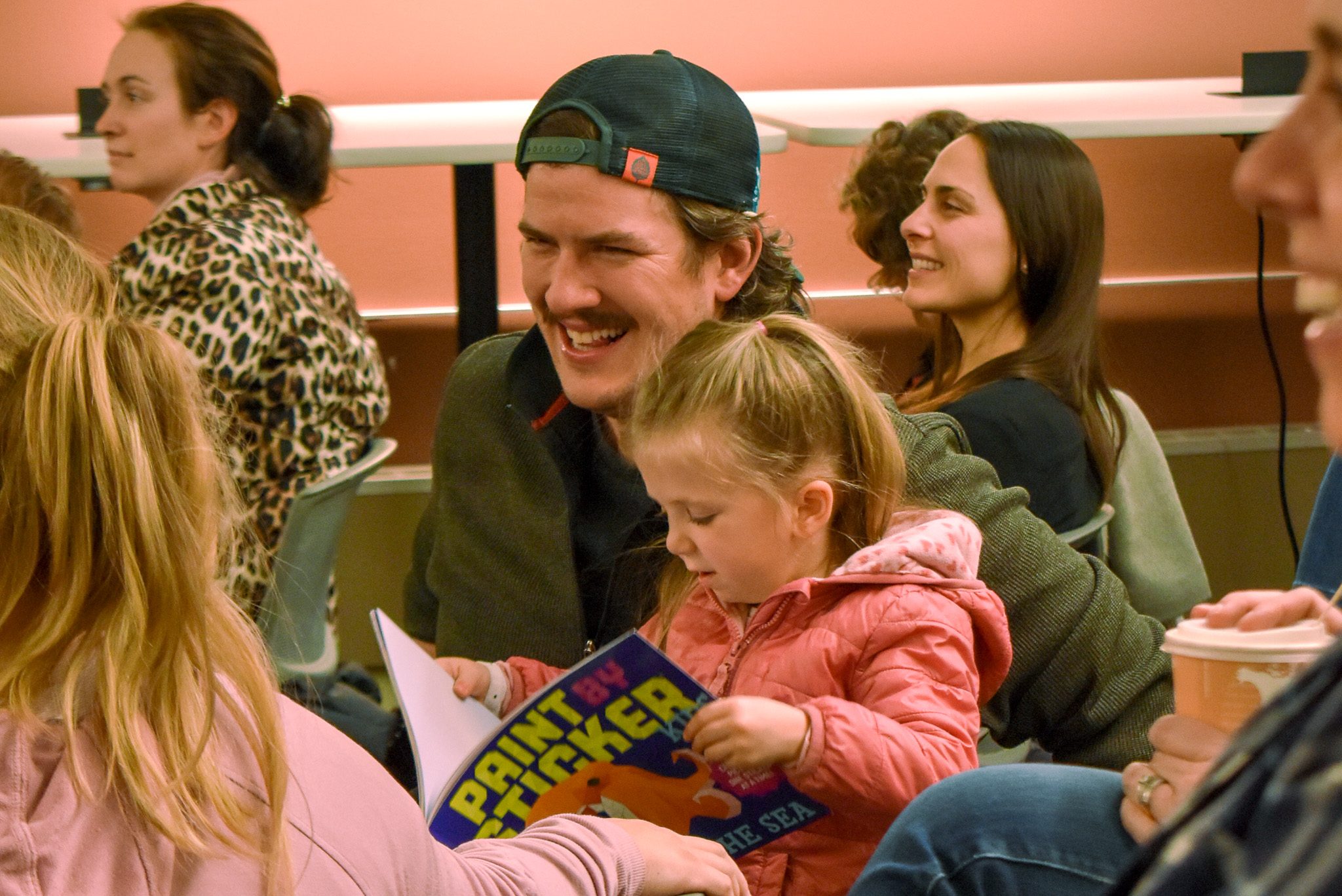 daughter reading a book seated on her father's lap