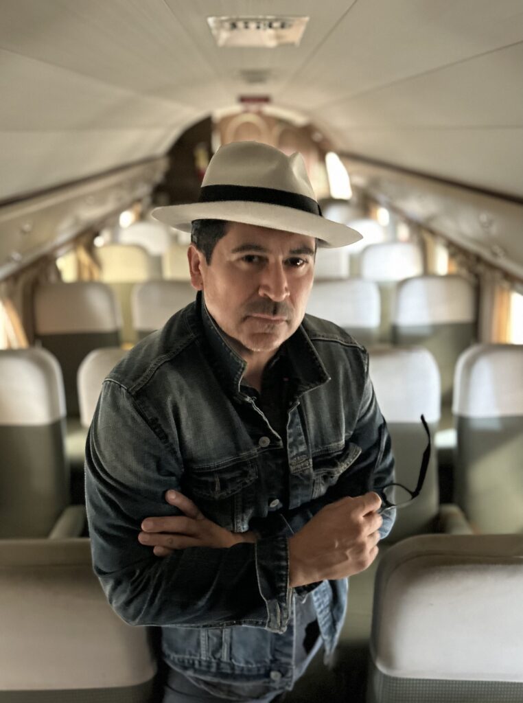 author tim hernandez posing for a photo in an old school bus